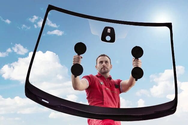 Man using suction cups for windshield replacement installation